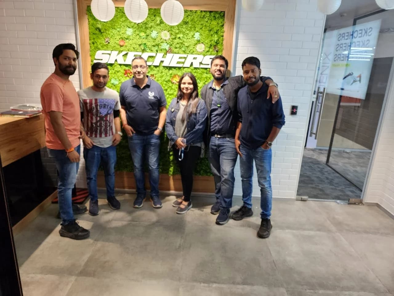 A group of Academy of Retail Excellence students photographed together. Sign visible in the photograph: Skechers.