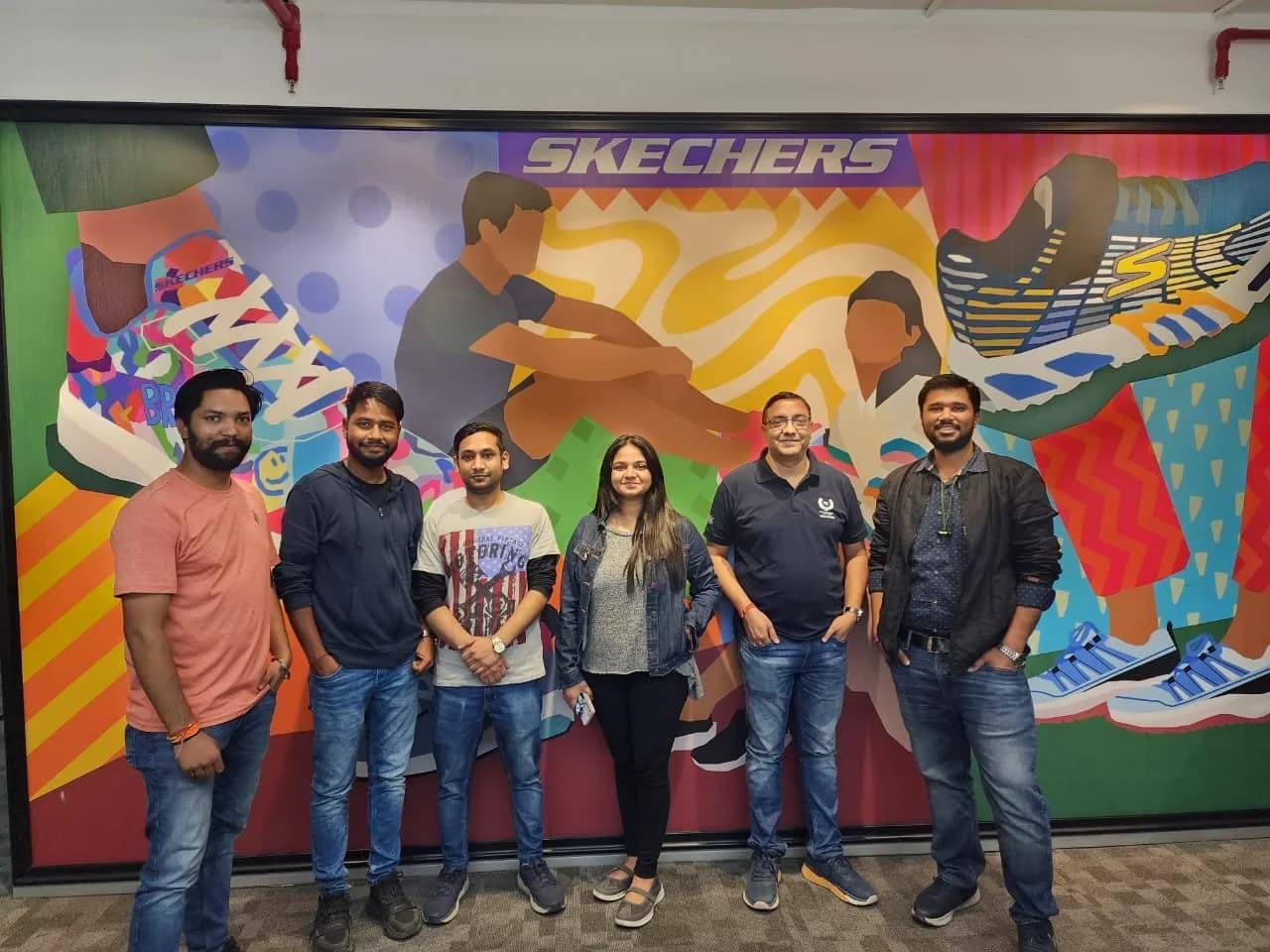 A group of Academy of Retail Excellence students photographed together. Sign visible in the photograph: Skechers.